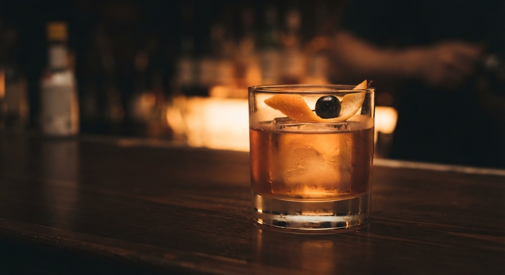 Old fashioned with orange peel and a cherry on a dark bar